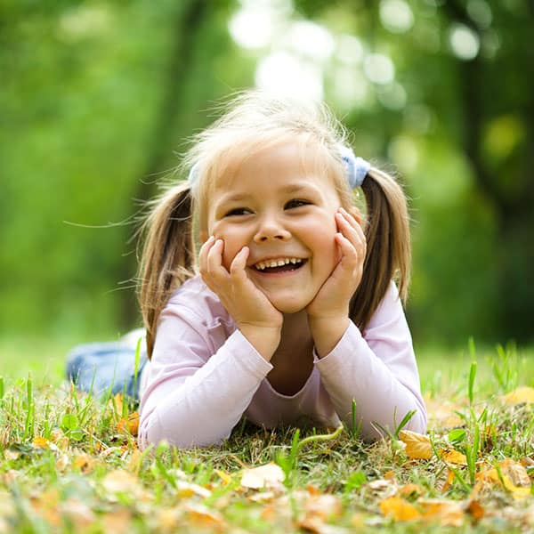 GirlinPigtailsSmilingOutdoors Young Girl in the Grass with Pigtails